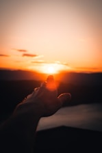 person holding sun during sunset