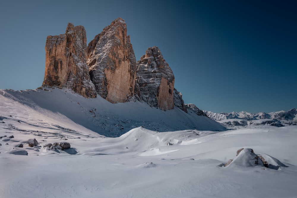 brown rocky mountain covered by snow under blue sky during daytime