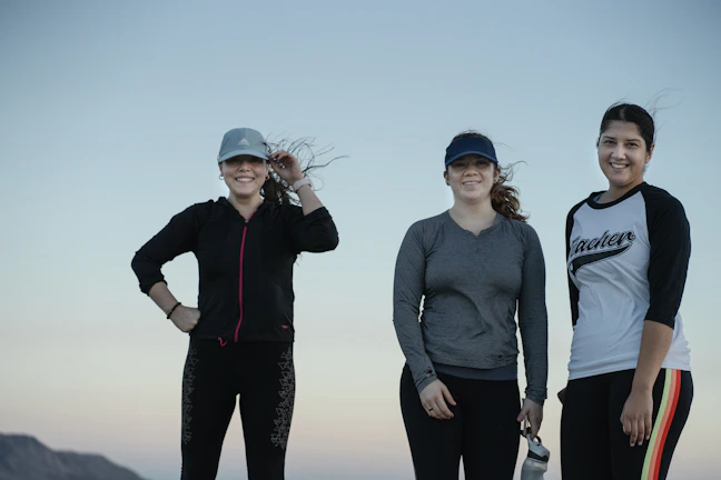 Group of women laughing joyfully after outdoor workout, wearing stylish minimalist activewear.