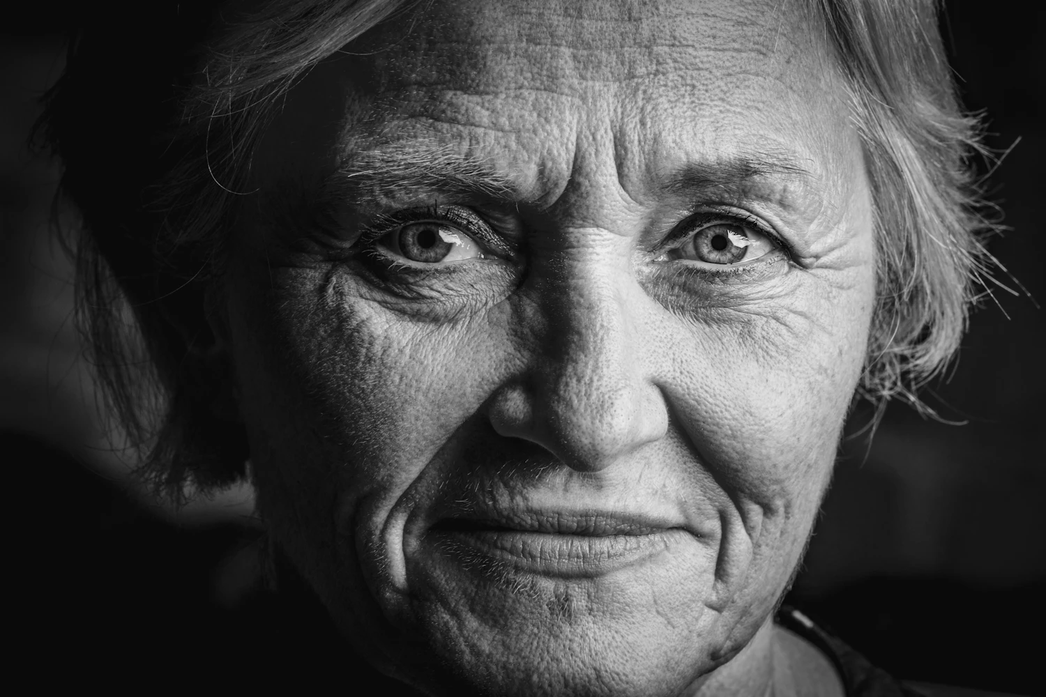An older woman with short grey hair, photographed in profile light