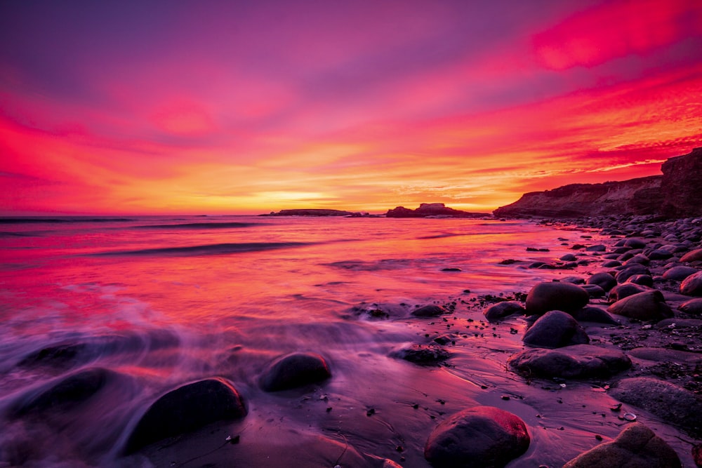 Spiaggia rocciosa durante il tramonto con cielo rosso