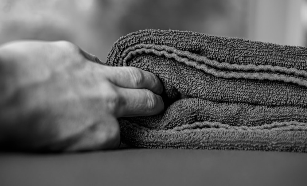foto in scala di grigi di una persona che tiene in mano un tessuto