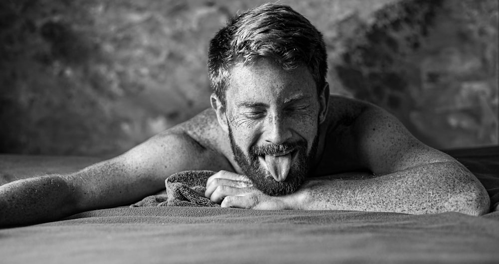 grayscale photo of man lying on wooden surface