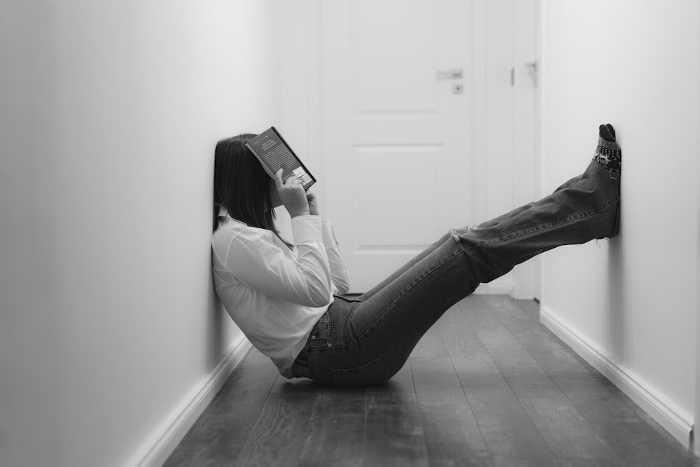 woman in white long sleeve shirt and black pants sitting on floor