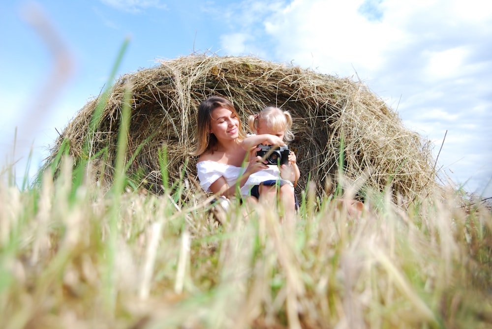 woman in white tank top lying on green grass field during daytime