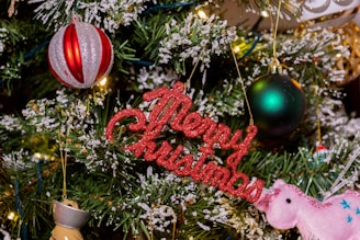 a christmas tree decorated with ornaments and a happy christmas sign