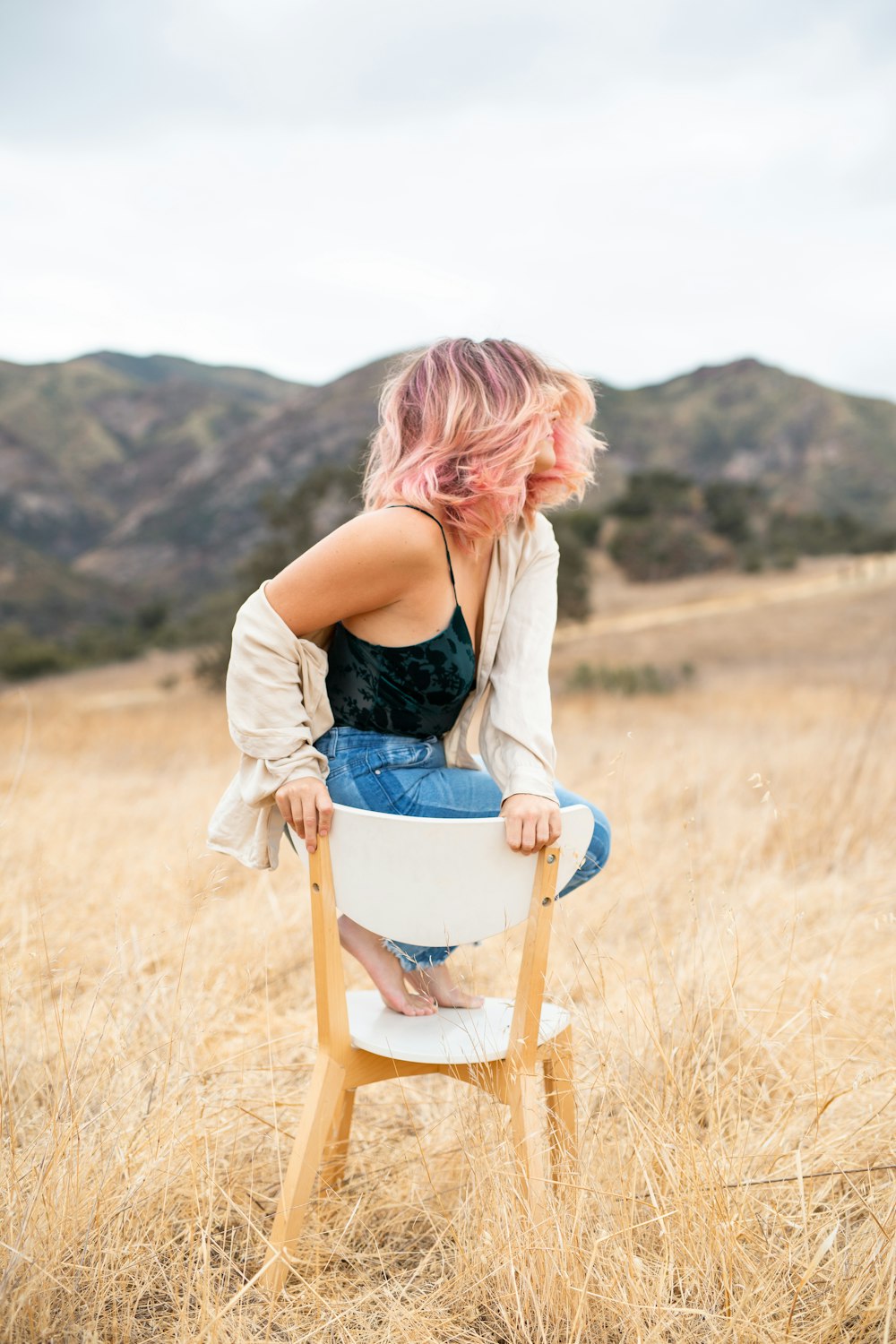 woman in black tank top and blue denim shorts sitting on brown wooden chair during daytime