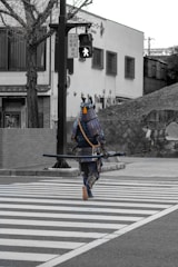 man in blue and black suit holding black rifle walking on pedestrian lane during daytime
