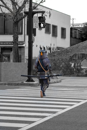man in blue and black suit holding black rifle walking on pedestrian lane during daytime