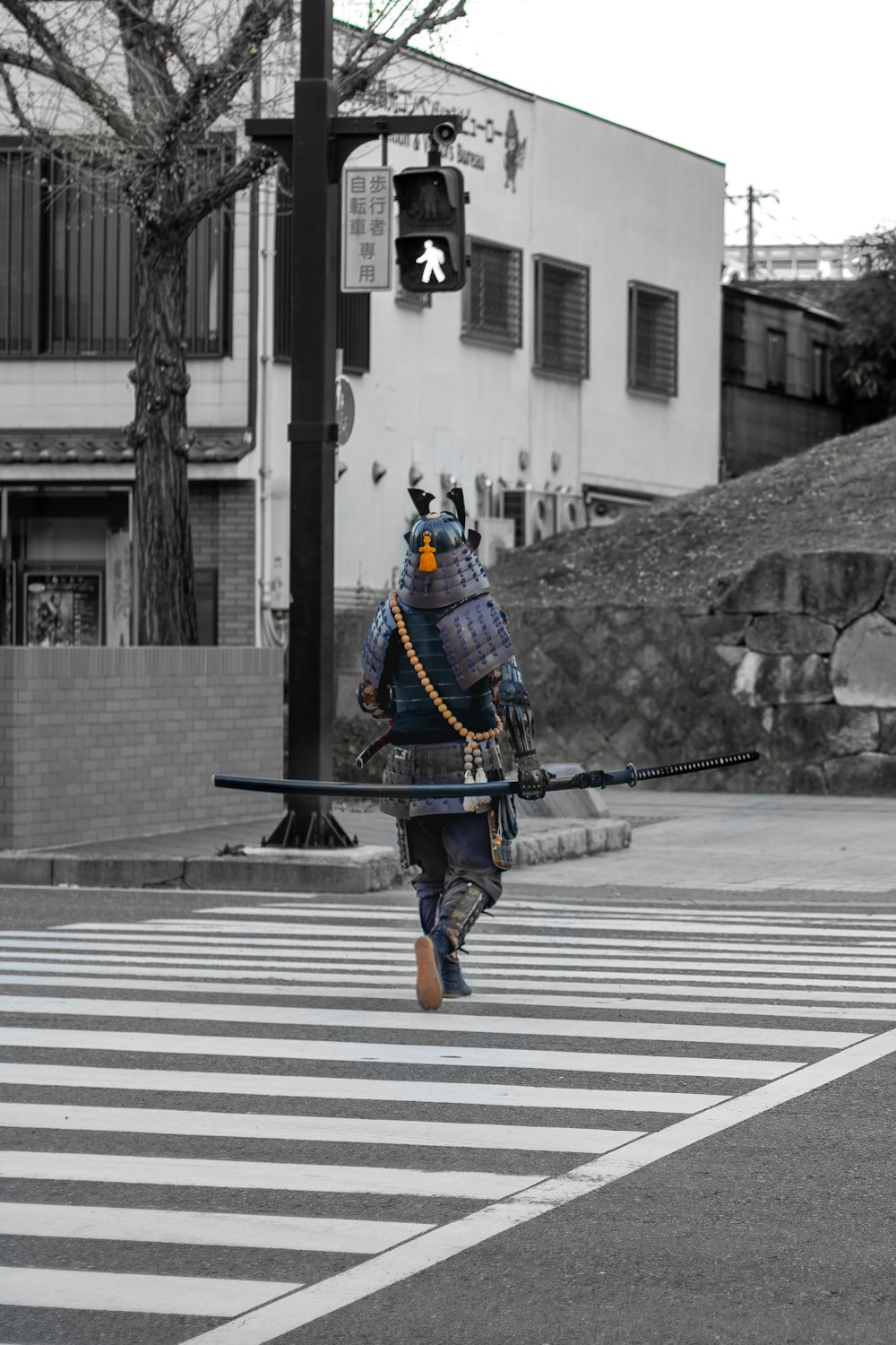 Homme en costume bleu et noir tenant un fusil noir marchant sur une voie piétonne pendant la journée