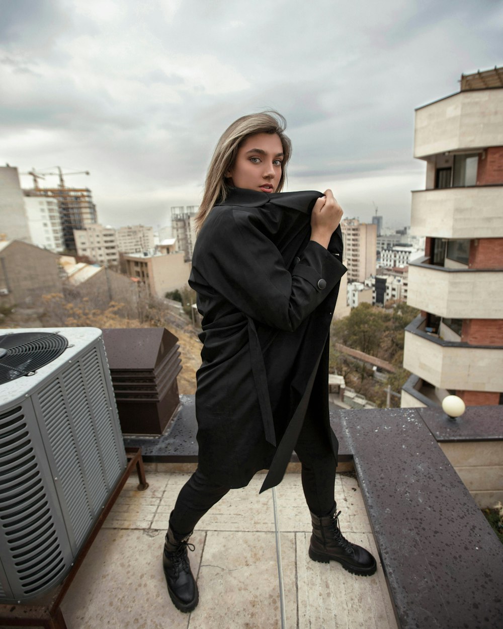 woman in black coat standing on brown wooden floor during daytime