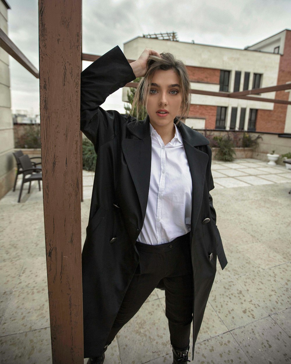 woman in black coat standing beside brown wooden post