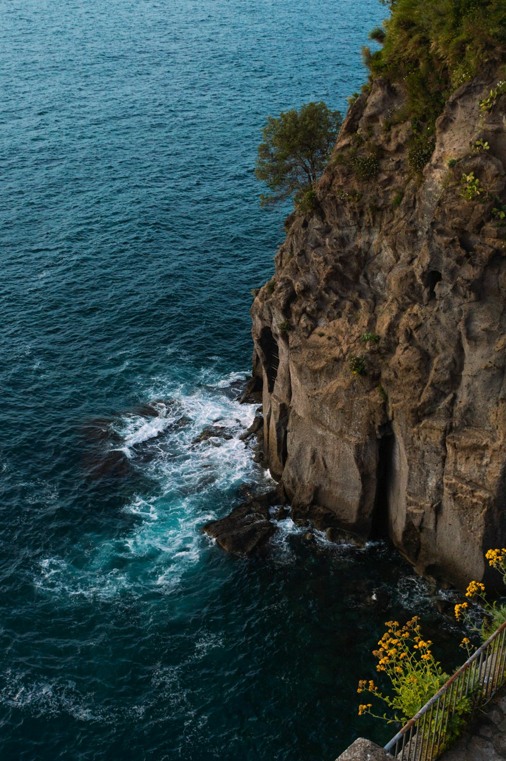 brown rocky mountain beside blue sea during daytime