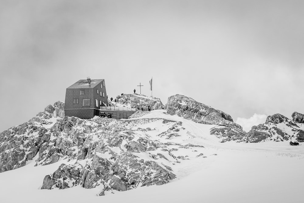grayscale photo of house on snow covered mountain