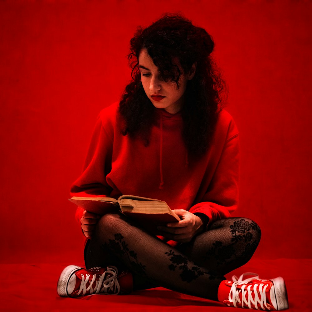Donna in camicia rossa a maniche lunghe seduta sul pavimento rosso
