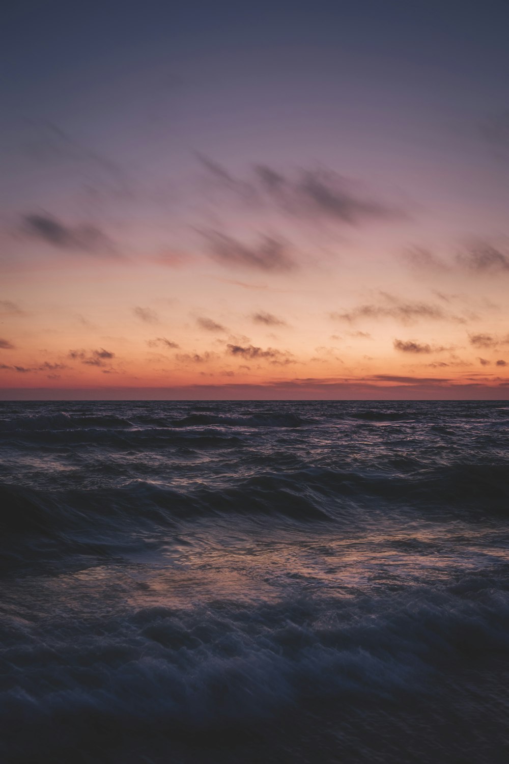 ocean waves under cloudy sky during sunset