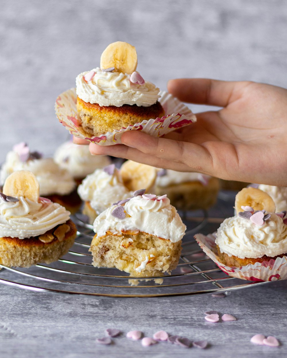 person holding two brown and white cupcakes