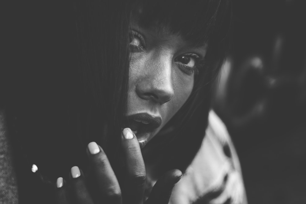 grayscale photo of woman covering her face with her hand