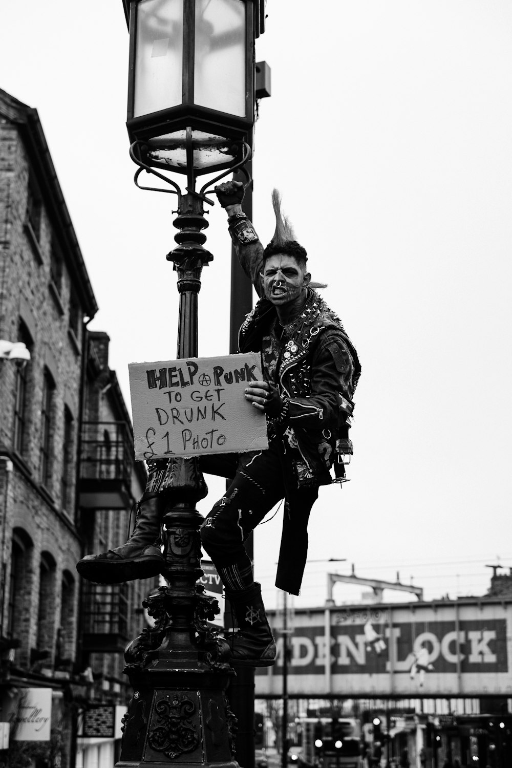 grayscale photo of man in jacket and pants holding signage