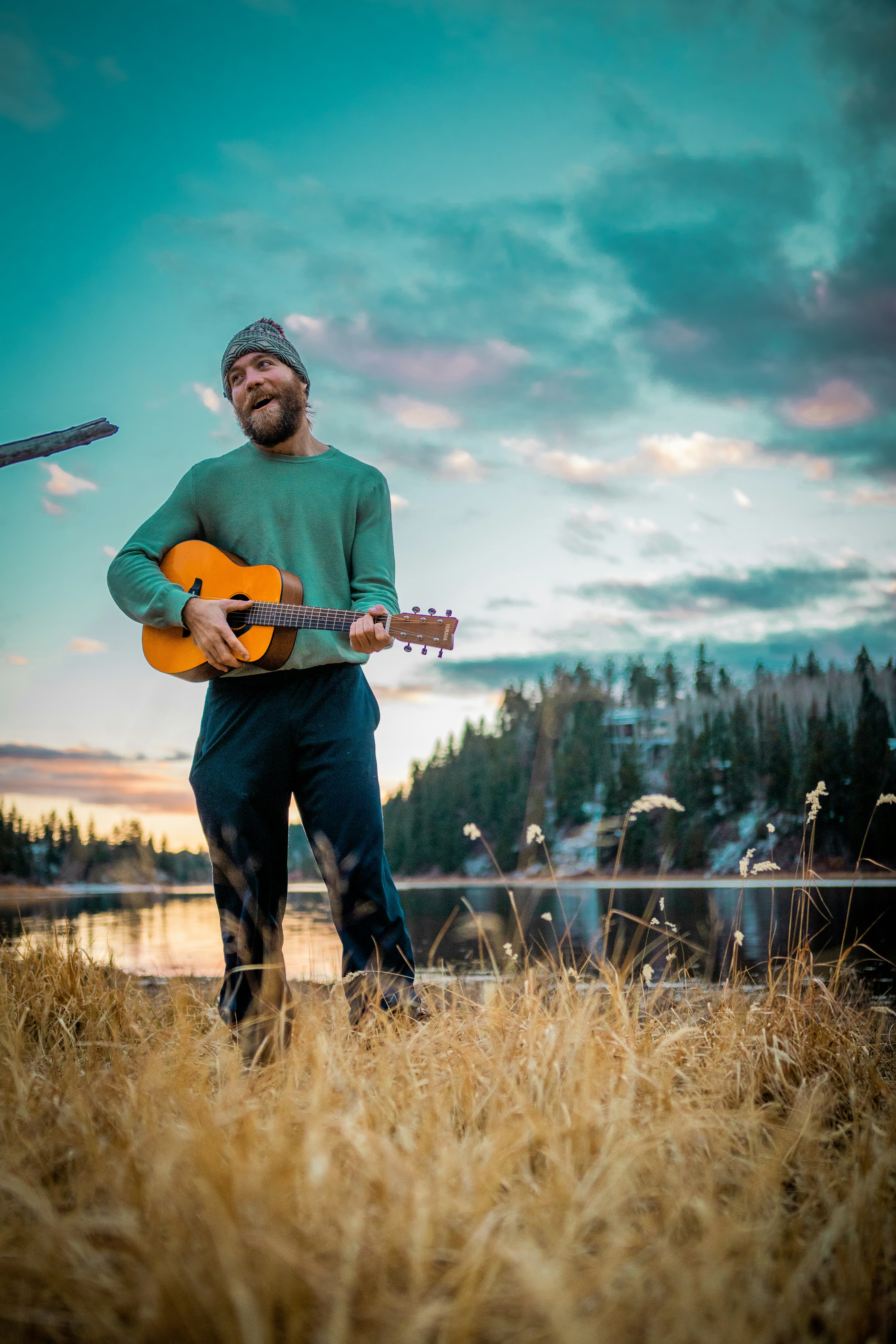 man in red crew neck t-shirt and blue denim jeans holding brown acoustic guitar