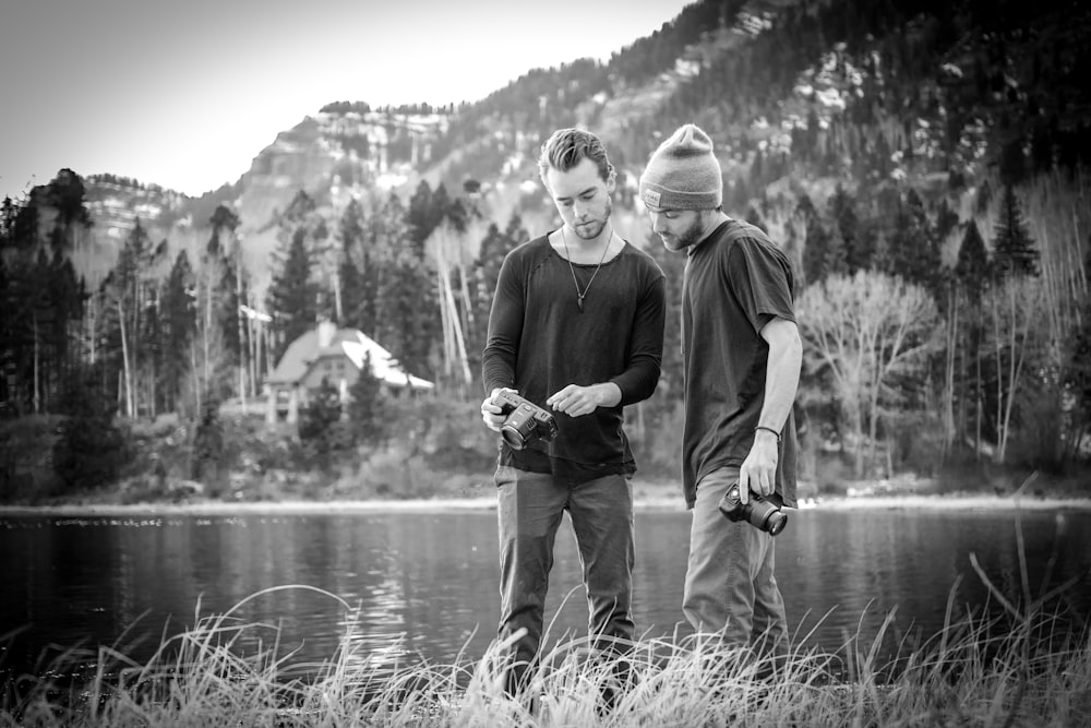 man and woman standing beside lake