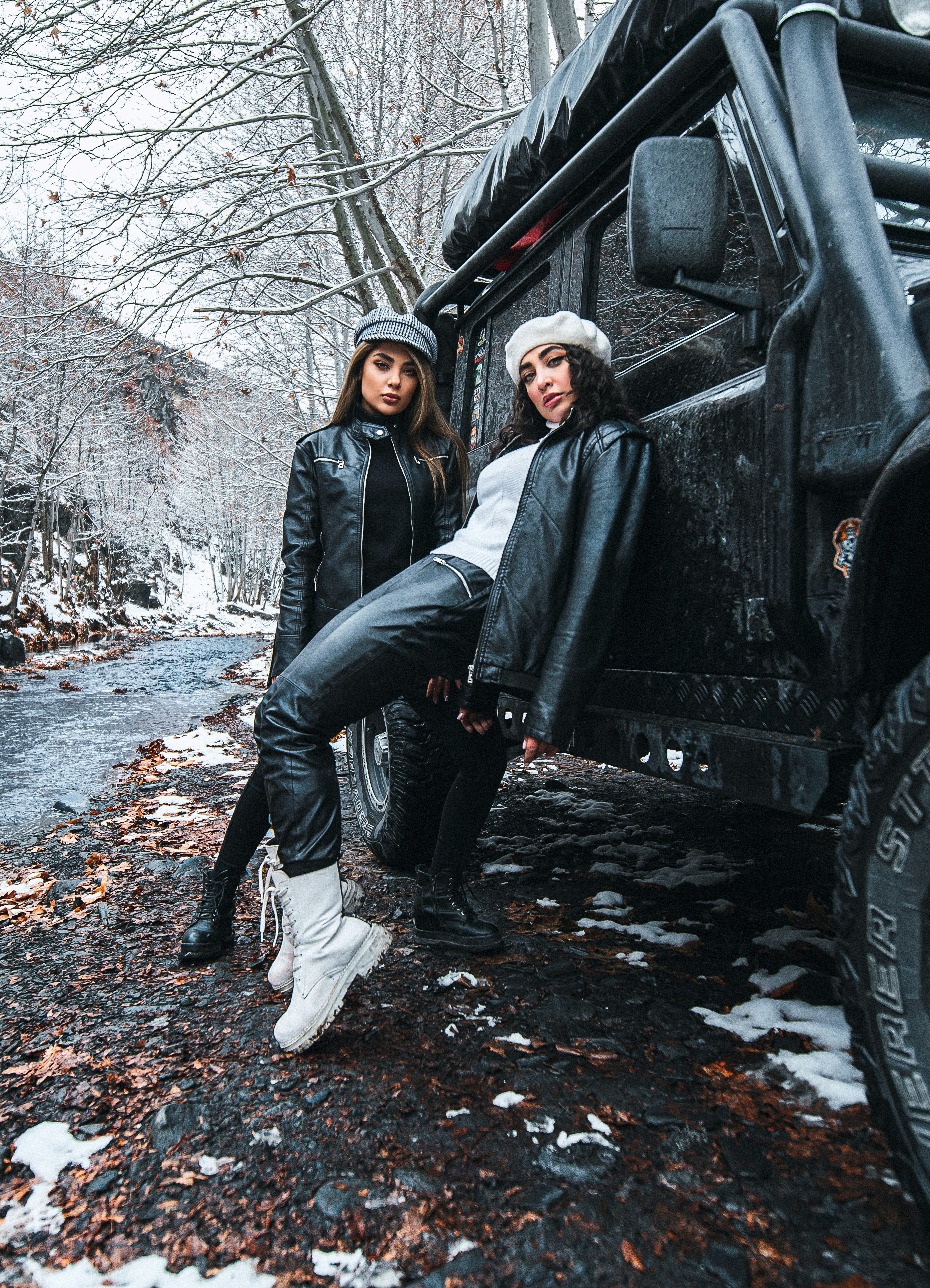 woman in black leather jacket and black pants leaning on black car