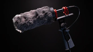 A sleek shotgun microphone positioned on a boom pole above a film set, capturing clear audio.