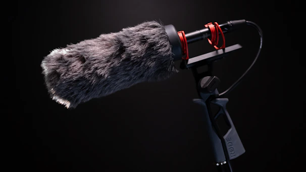 A sleek shotgun microphone positioned on a boom pole above a film set, capturing clear audio.