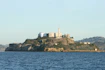 Historic black-and-white photo of Alcatraz prison's main cellhouse against a foggy San Francisco Bay backdrop.