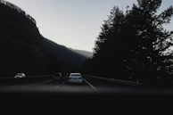 A panoramic view of a Yoocabs vehicle convoy making its way through a winding mountain highway during golden hour.