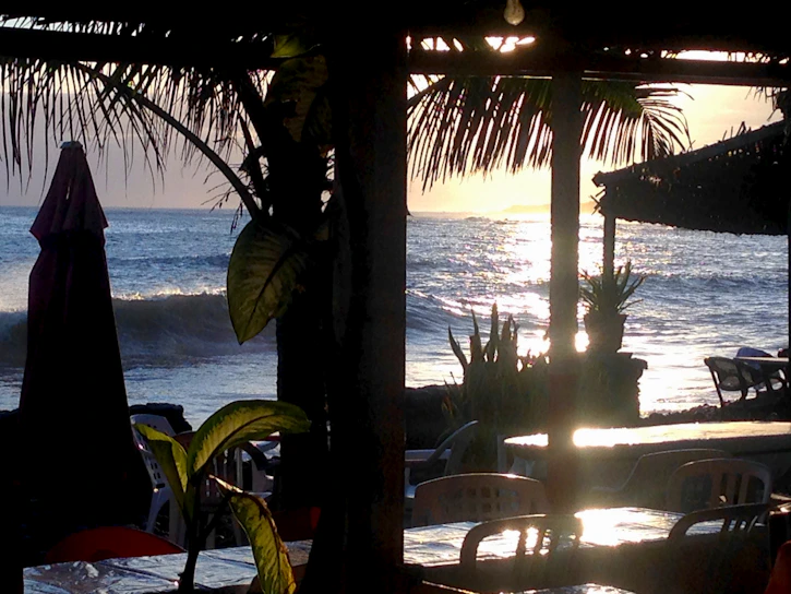 Sunset view over the beachside patio of Costa Dulce with colorful sunda dishes on the table.