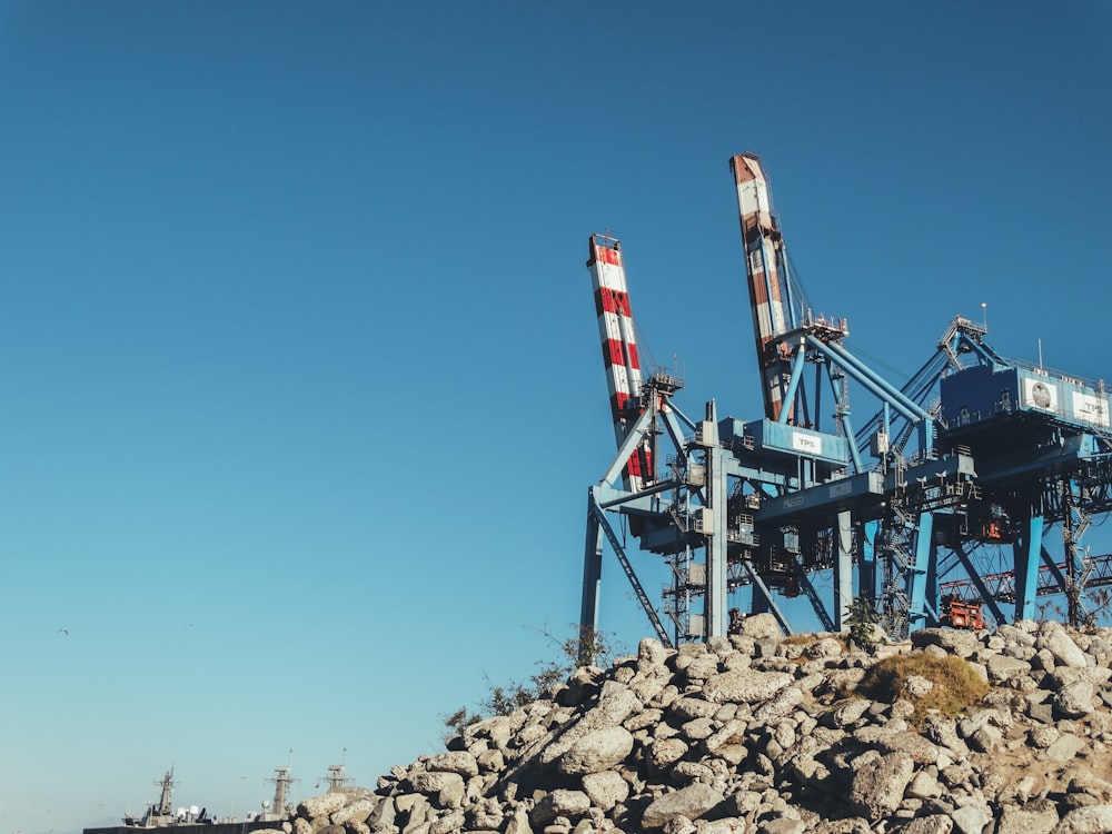 white and red metal tower on brown rocky field under blue sky during daytime