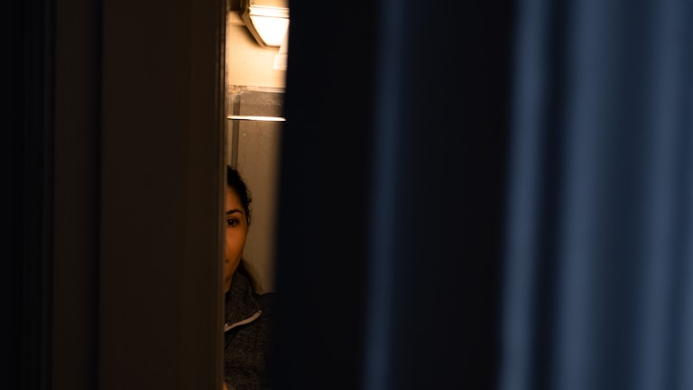 A discreet investigator observing a suspect from a shadowed alley.