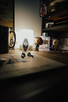 A cozy desk setup with pop culture memorabilia, including comic books, anime figures, and movie posters.