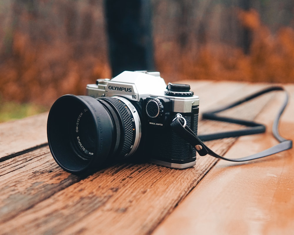 schwarz-silberne DSLR-Kamera auf braunem Holztisch