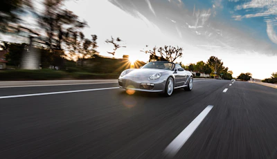 Dynamic shot of a luxury sports car speeding on an open highway at dusk.