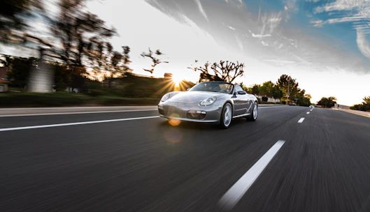 A dynamic shot of a sports car in motion on an open road at sunset.