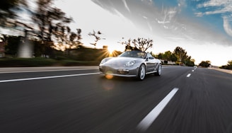 A dynamic shot of a sports car speeding on an open road at dusk.