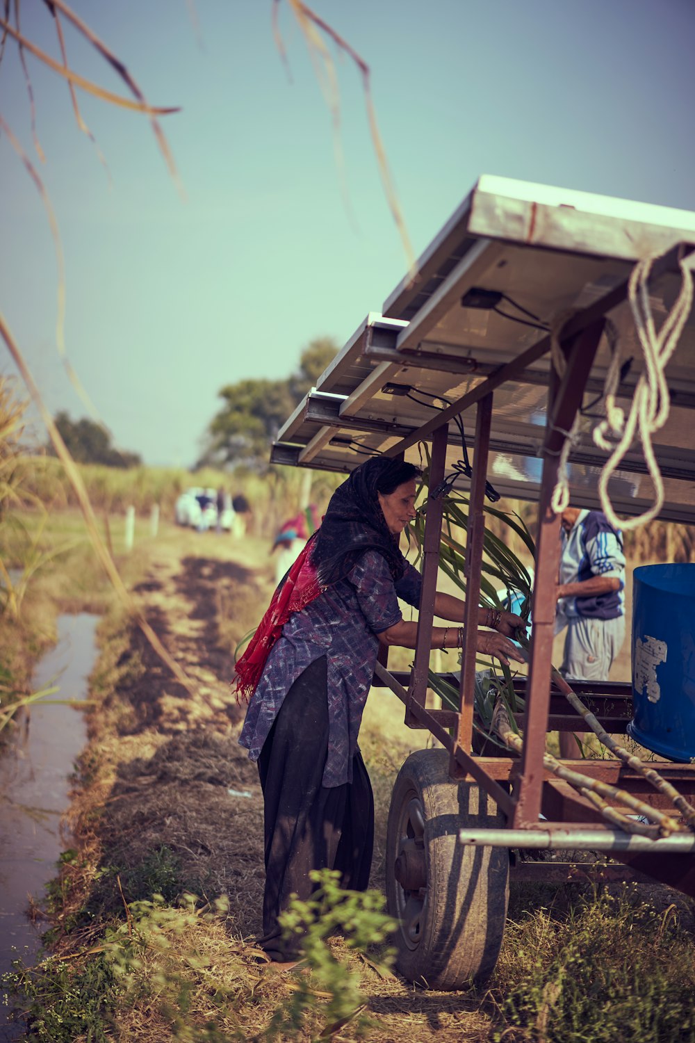 woman in red and black scarf standing near brown wooden shed during daytime