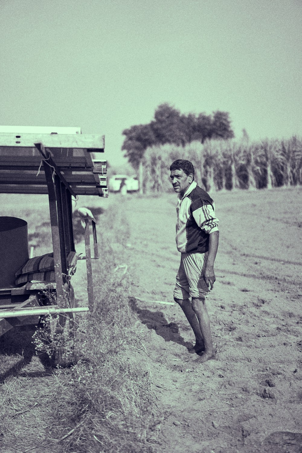 man in black and red shirt and brown shorts standing beside black car