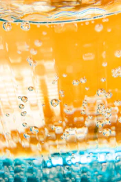 Close-up of a Hydranit sachet dissolving in a glass of sparkling water with fresh turquoise and blue tones.