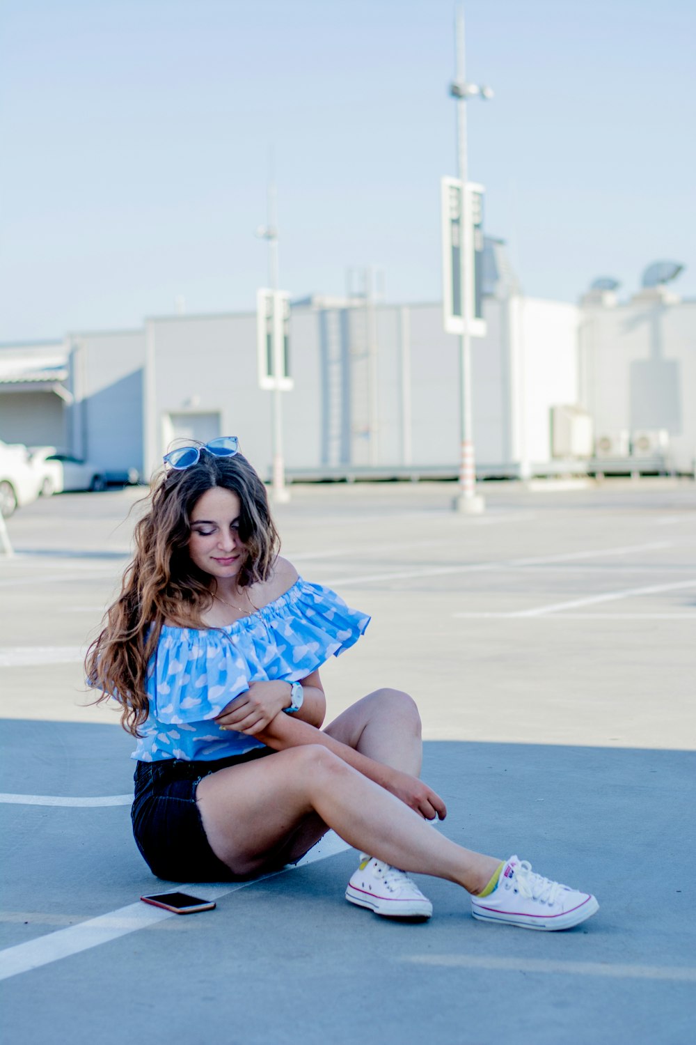 woman in blue shirt sitting on blue concrete floor during daytime