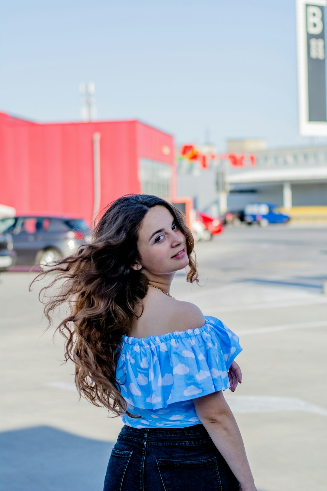 woman in blue and white floral off shoulder dress standing on street during daytime