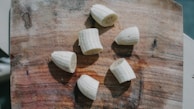 A rustic kitchen scene showing banana chips being sliced by hand on a wooden board.