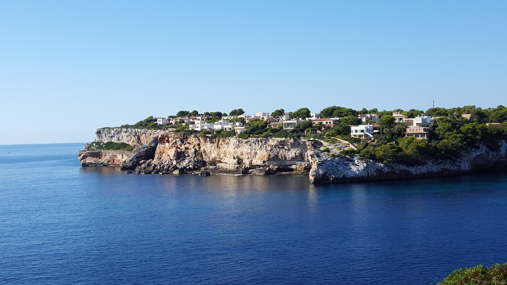 brown and green rock formation near blue sea under blue sky during daytime