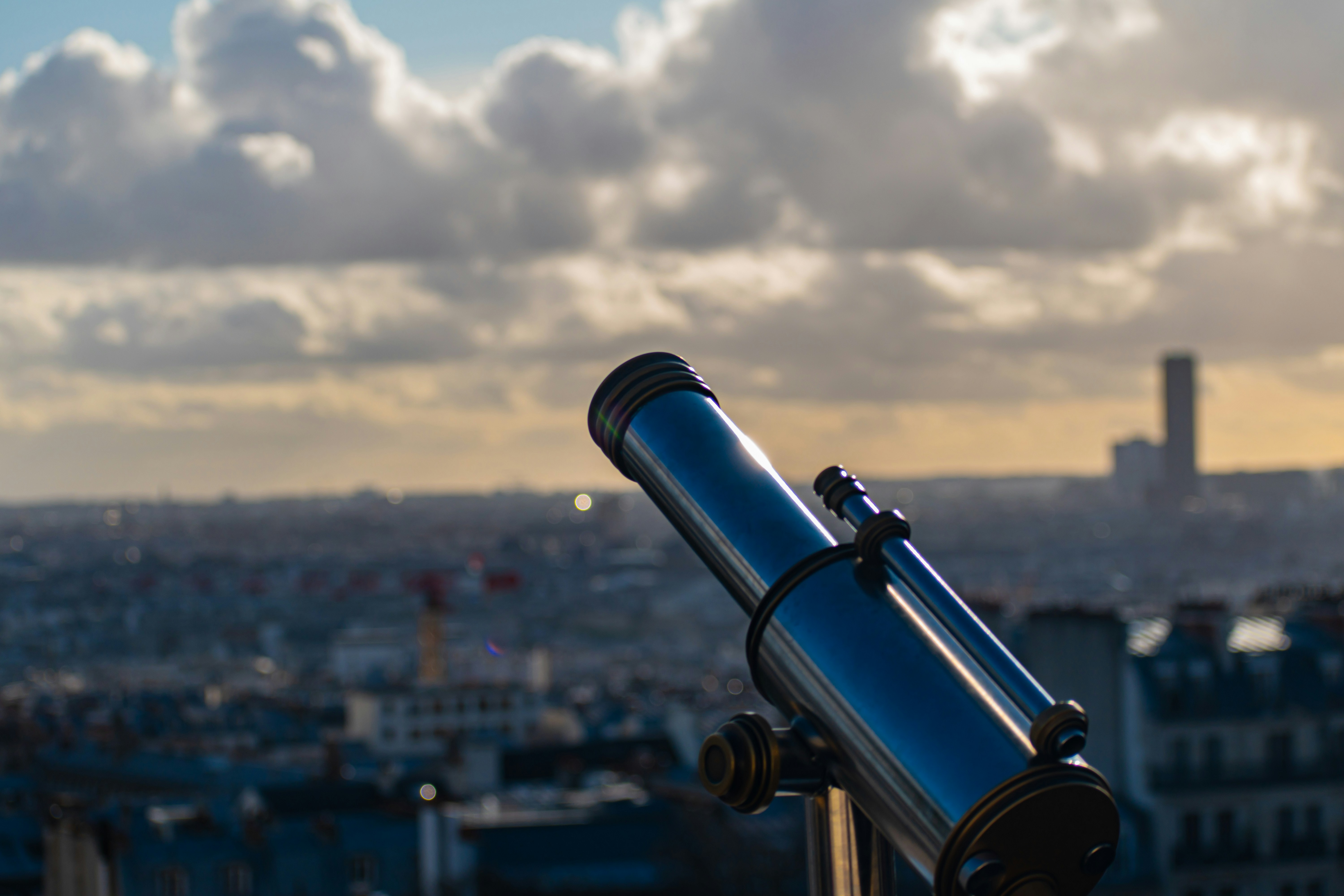 black telescope in front of city buildings during daytime