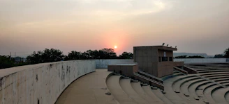 A rustic auditorium nestled in a barren landscape under a vast sky at dusk.
