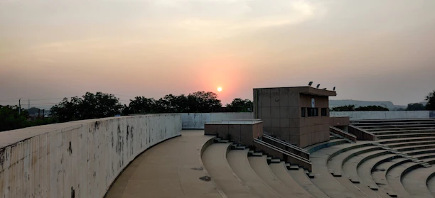 A rustic auditorium nestled in a barren landscape under a vast sky at dusk.