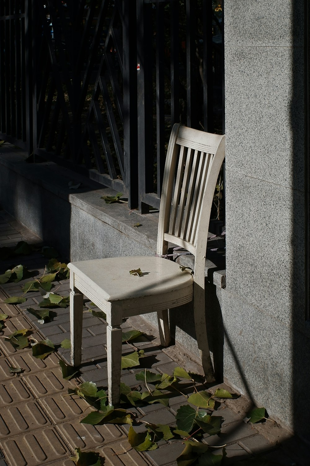 white wooden chair beside gray concrete wall