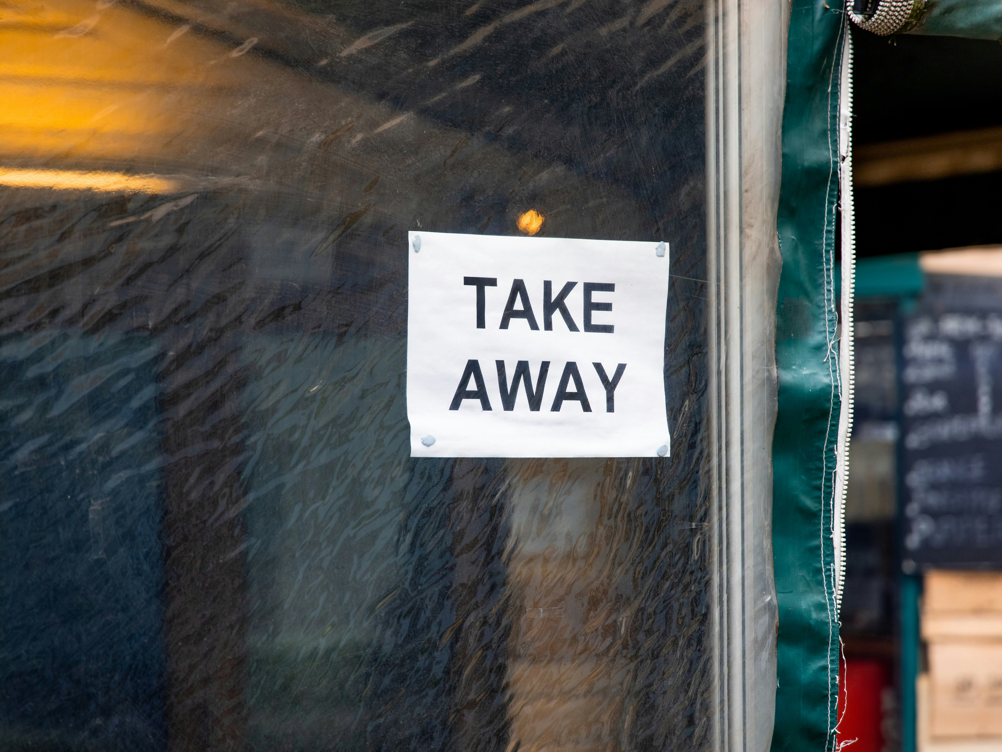 Makeshift sign in restaurant window that reads, “Take Away”